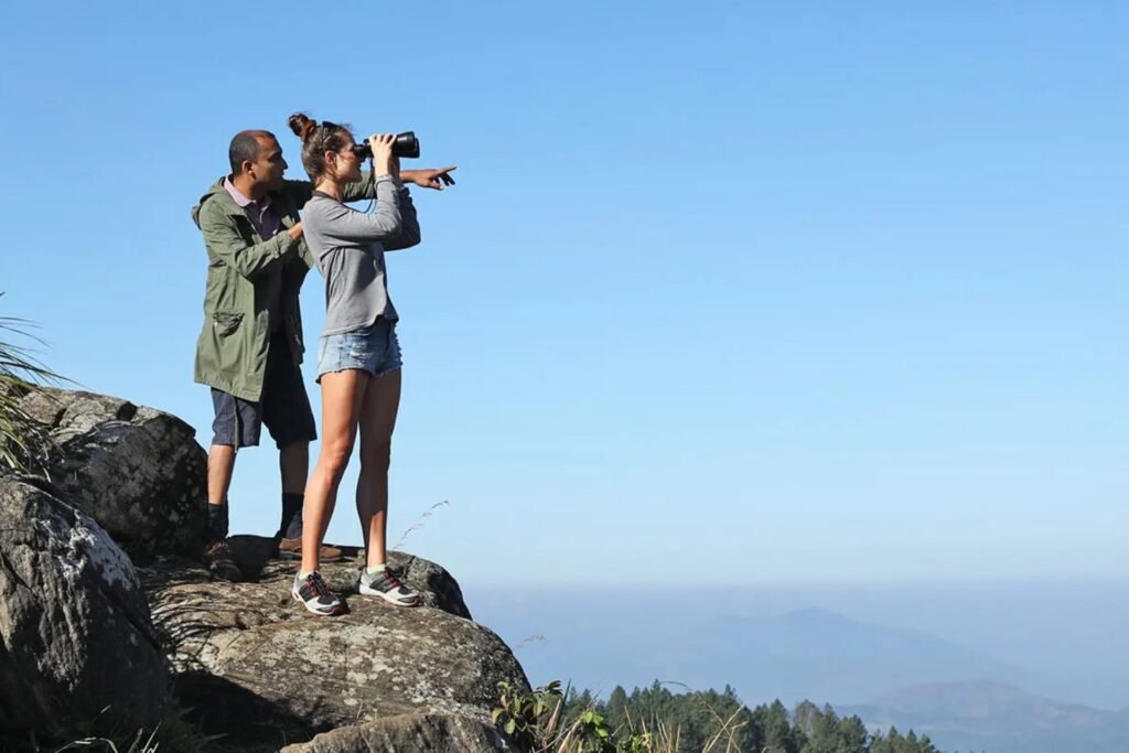 Two birdwatchers with binoculars and a camera on a clifftop