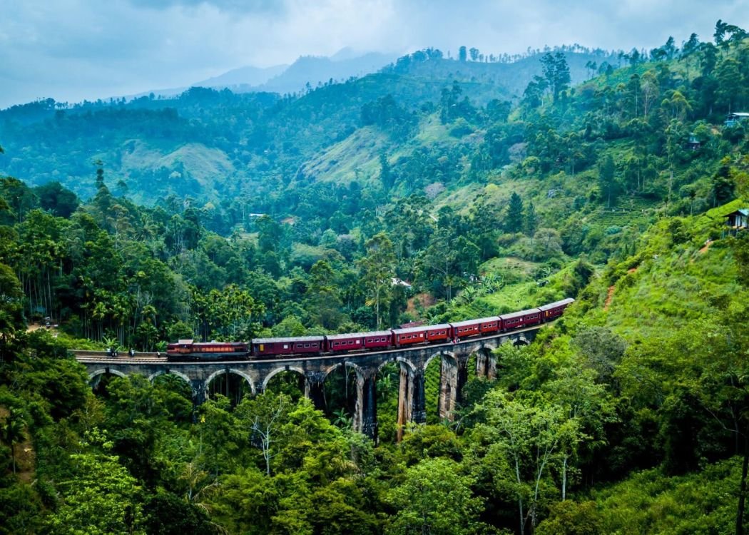 Red train crossing the Nine Arch Bridge in Ella, Sri Lanka