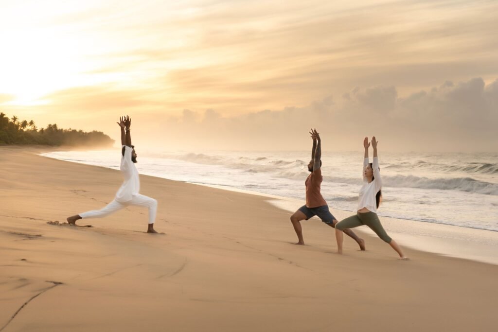 Group practising yoga on the beach at sunset
