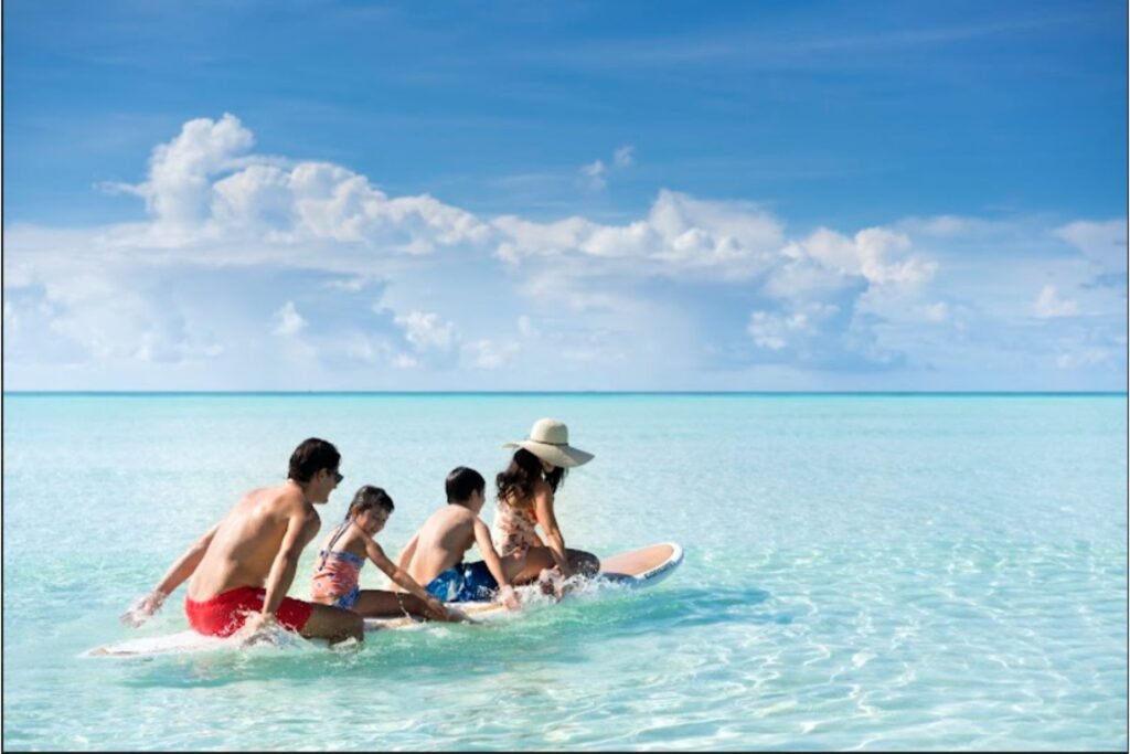 Family sitting on a sandbank in shallow turquoise water
