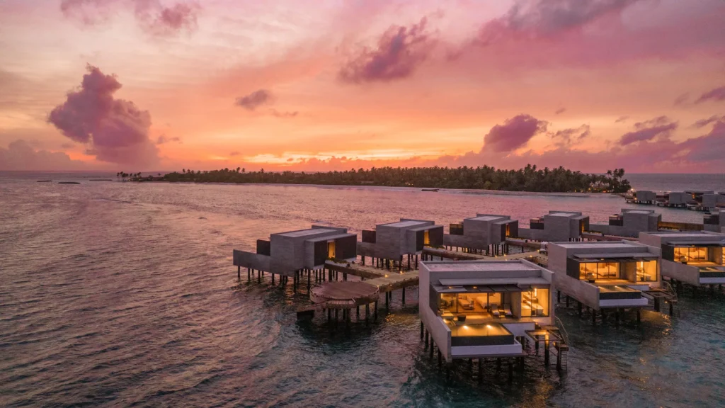 Overwater villas lit at sunset at Alila Kothaifaru Maldives