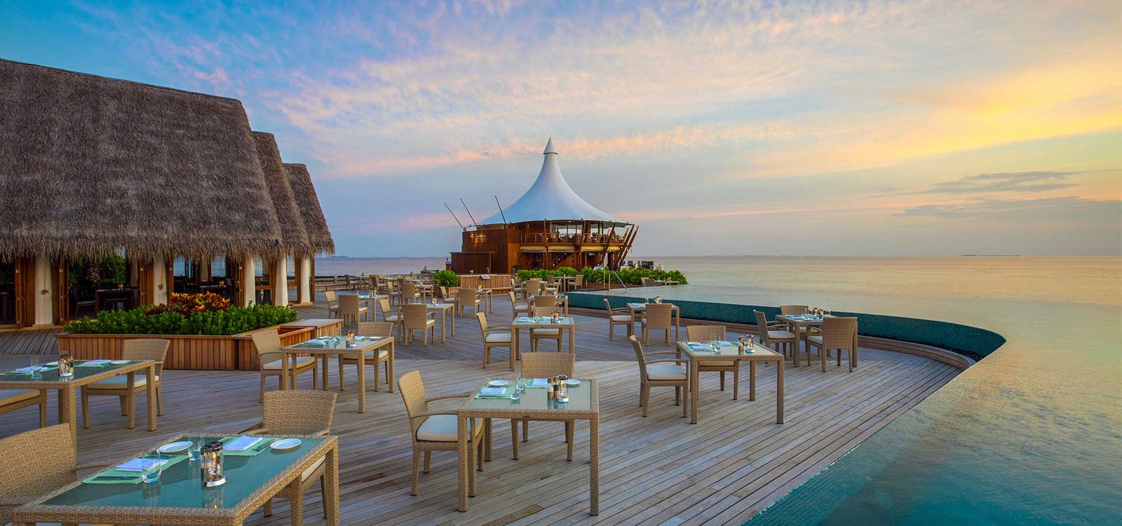 Overwater restaurant deck at sunset at Baros Maldives
