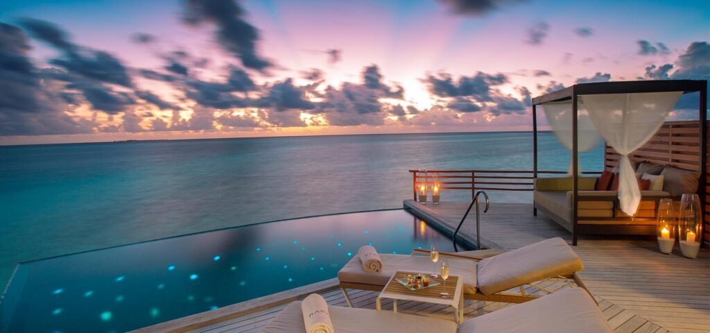 Overwater deck with a daybed at sunset at Baros Maldives