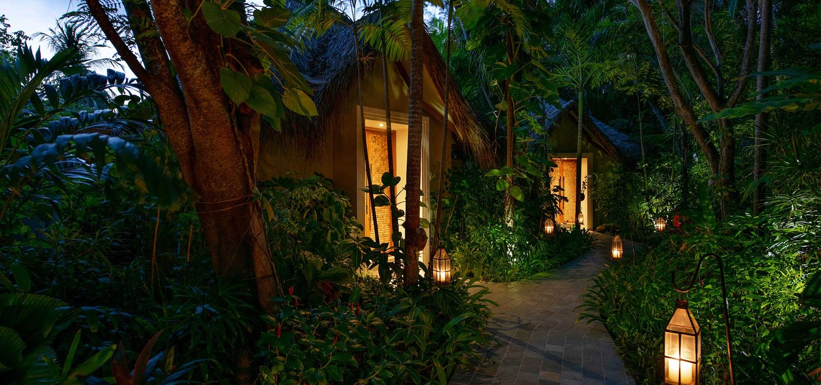 Lantern-lit garden path between the villas at Baros Maldives