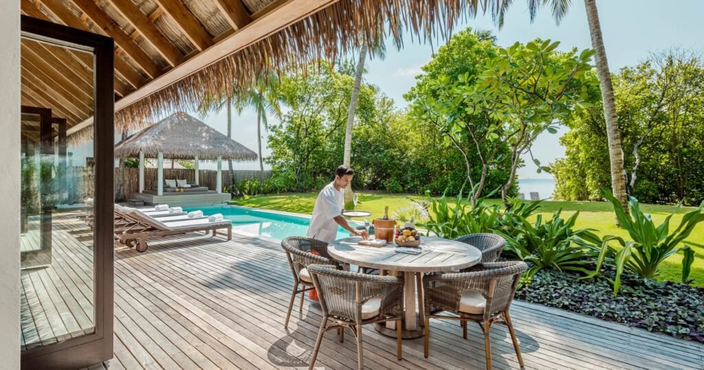 Villa deck with a dining table and pool at COMO Maalifushi