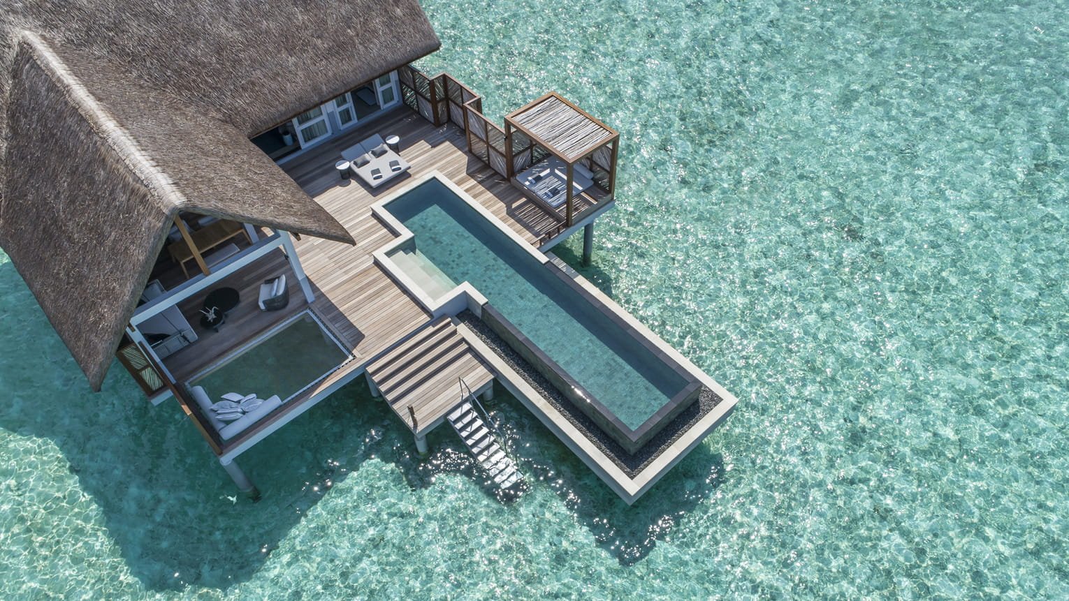 Aerial view of an overwater villa and pool at Four Seasons Landaa Giraavaru