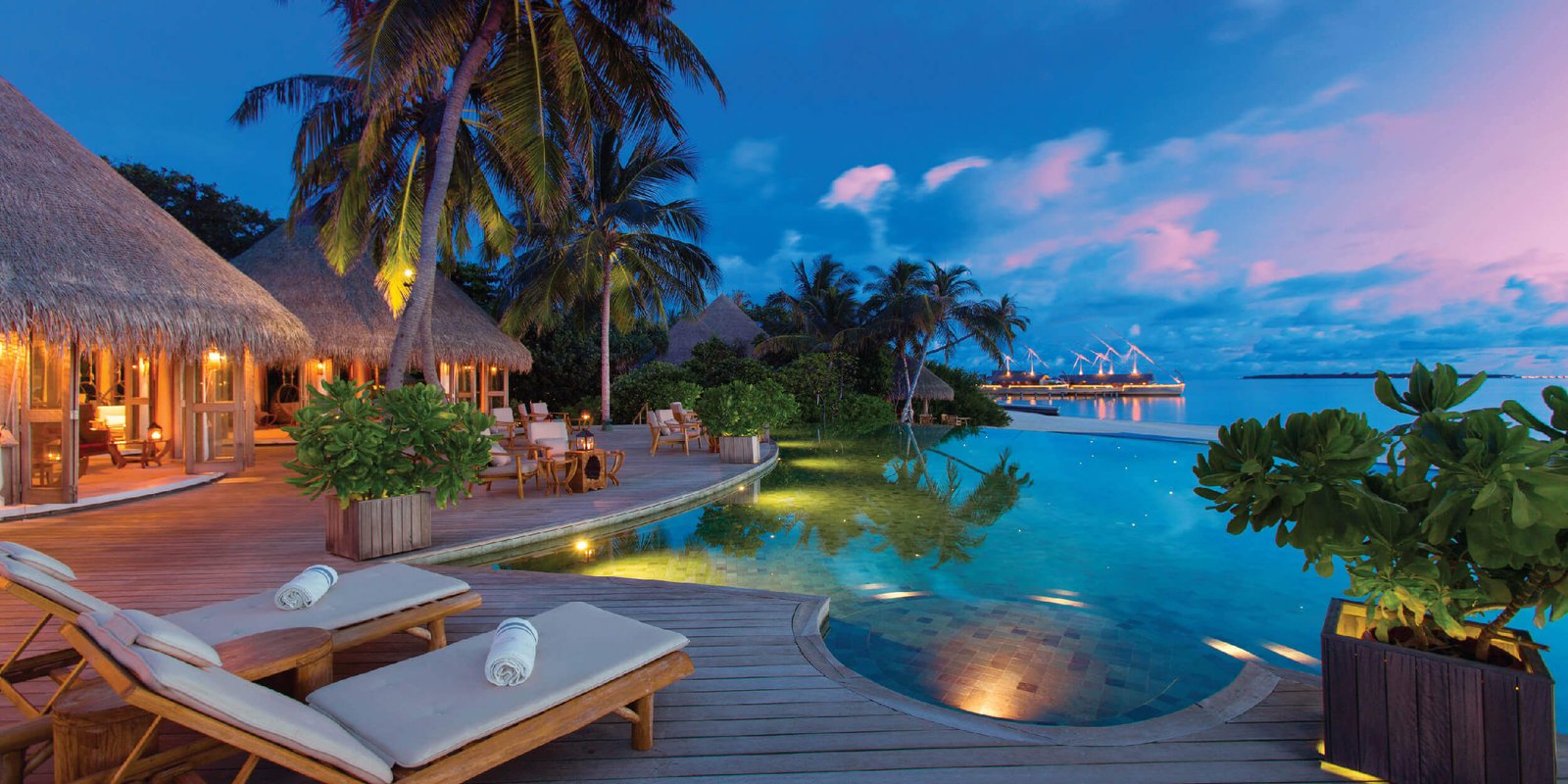Resort pool and deck at dusk at Milaidhoo Island