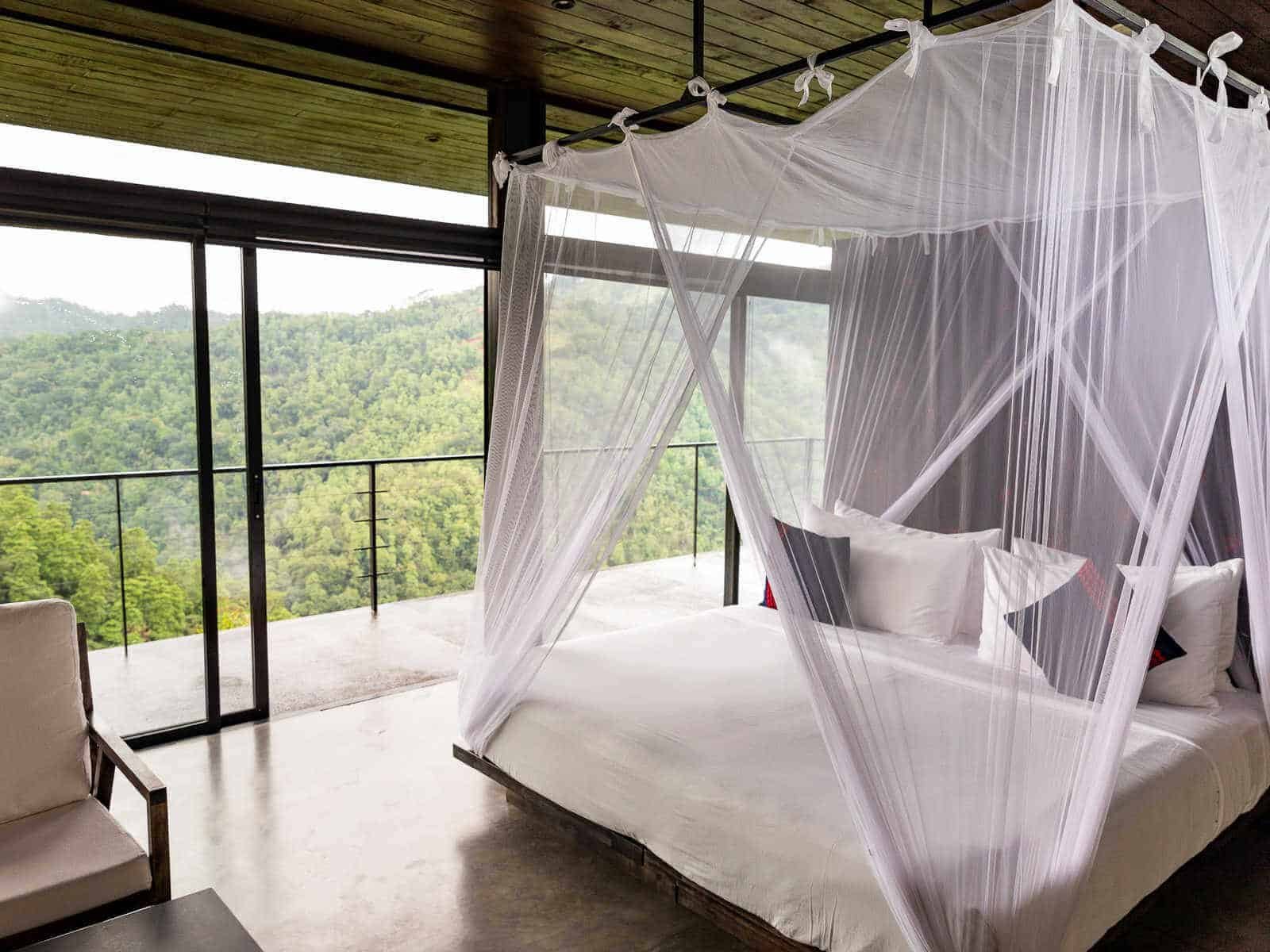Bedroom with mosquito netting and hill views at Santani Wellness Kandy