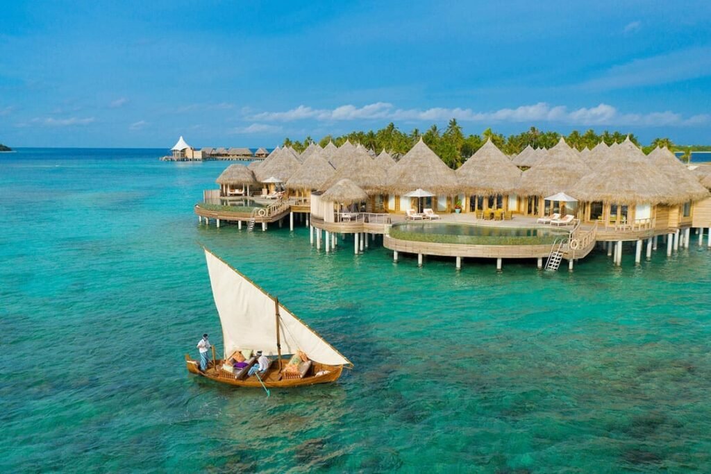 Traditional dhoni sailing past an overwater house at The Nautilus Maldives